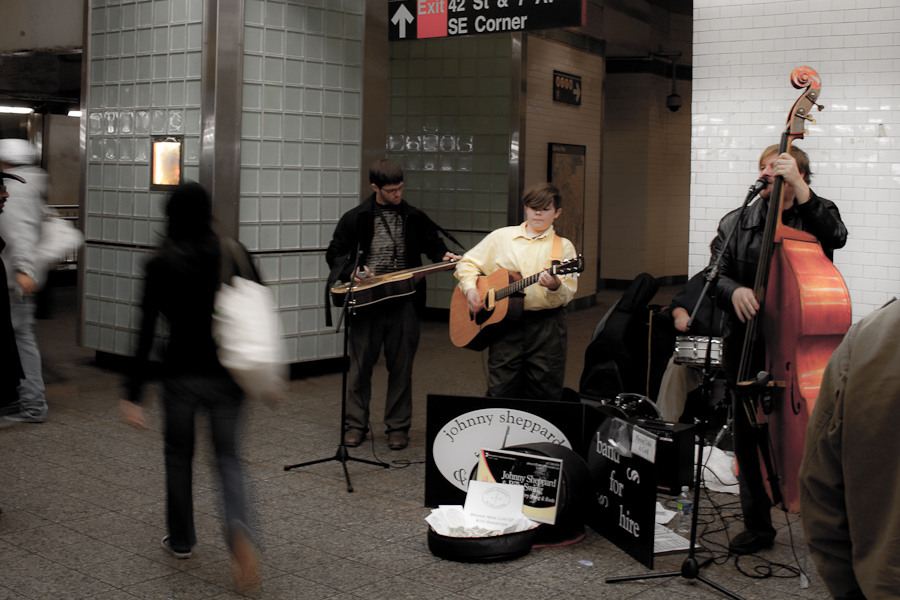 Musiciens dans une station de métro à New-York. Un chanteur/contrebassiste, un guitariste, et un guitariste slide. Un panonceau indique le nom du groupe : Johnny Sheppard & Billy Swing
